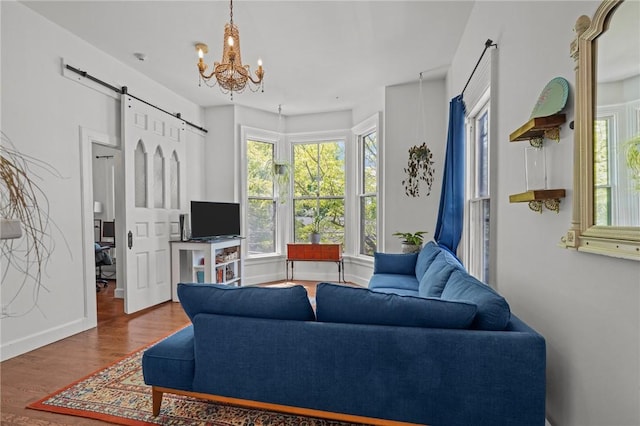 living room with a barn door, plenty of natural light, wood finished floors, and a chandelier