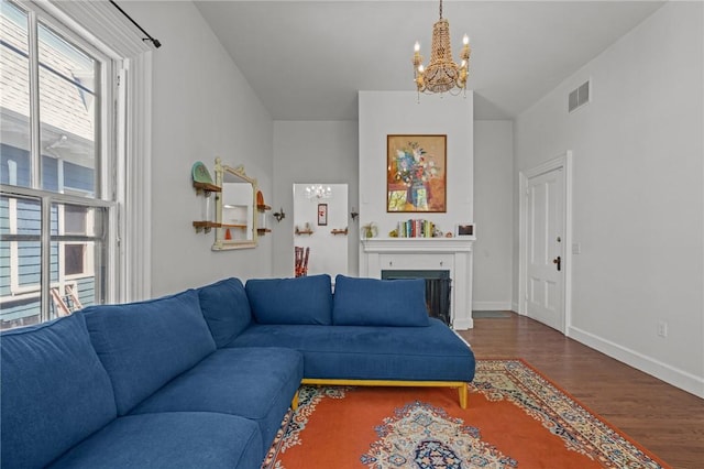 living area featuring a chandelier, wood finished floors, a fireplace, and baseboards