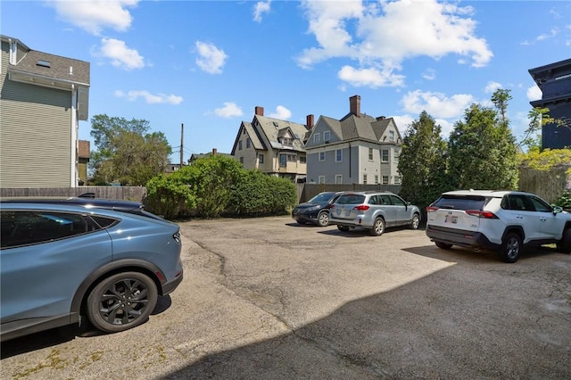 uncovered parking lot with a residential view and fence