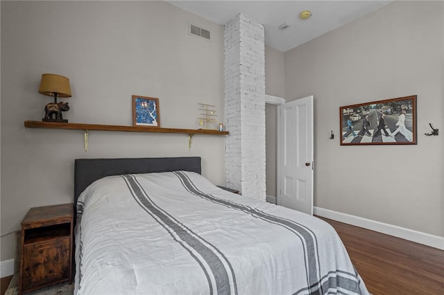 bedroom featuring baseboards, wood finished floors, and a high ceiling
