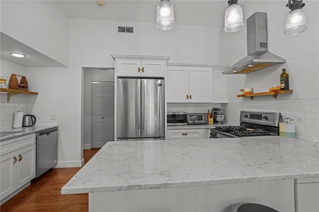 kitchen featuring appliances with stainless steel finishes, open shelves, wall chimney exhaust hood, decorative backsplash, and a peninsula