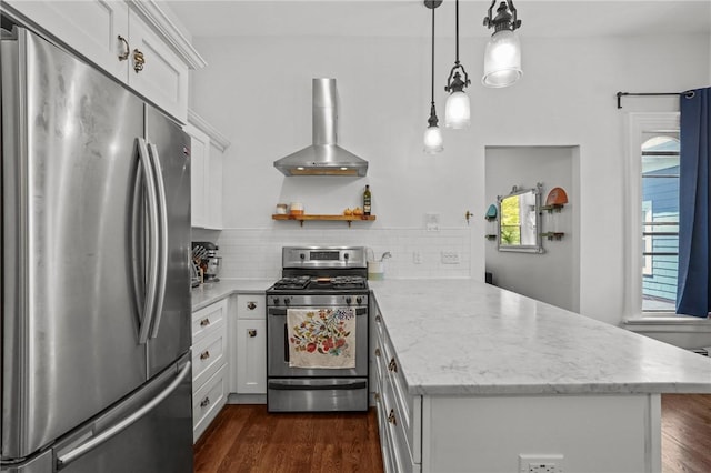 kitchen featuring appliances with stainless steel finishes, wall chimney exhaust hood, a peninsula, white cabinets, and tasteful backsplash