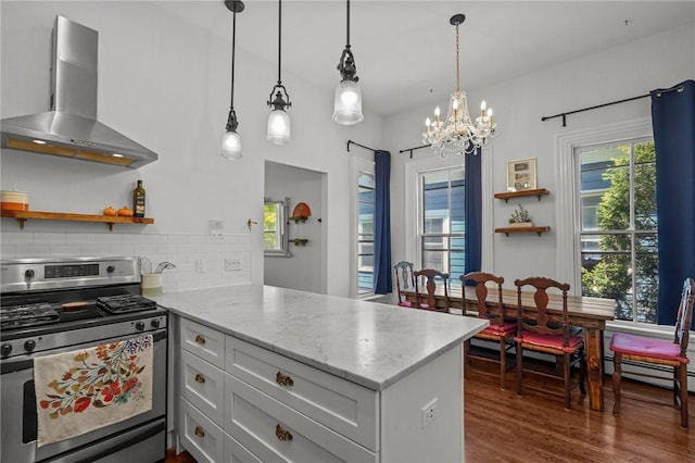 kitchen featuring stainless steel range with gas cooktop, wall chimney range hood, open shelves, a peninsula, and a chandelier