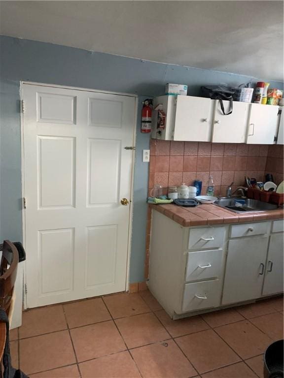31 Ponagansett Ave, Providence, RI 02909 - kitchen with backsplash, tile countertops, light tile patterned floors, a sink, and white cabinets