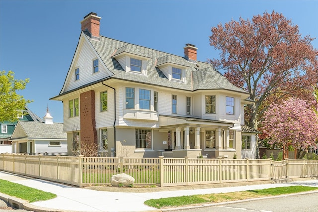 349 Wayland Ave, Providence, RI 02906 - victorian home with a porch, a chimney, a fenced front yard, and roof with shingles