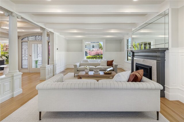 349 Wayland Ave, Providence, RI 02906 - living room featuring decorative columns, light wood-style flooring, a premium fireplace, a decorative wall, and wainscoting