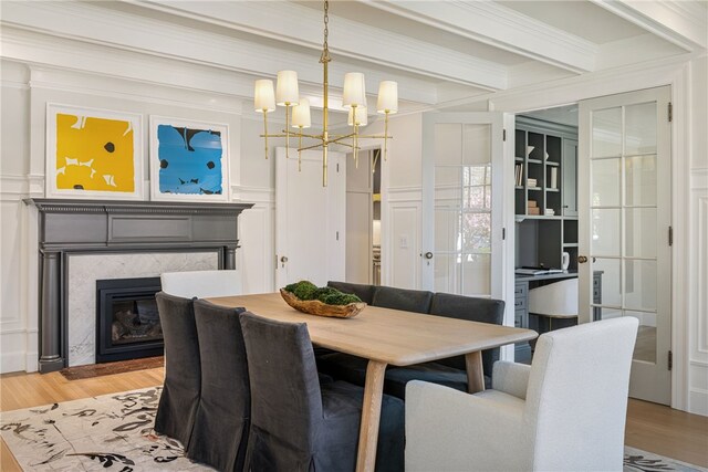 349 Wayland Ave, Providence, RI 02906 - dining space with a high end fireplace, a chandelier, beamed ceiling, light wood-type flooring, and a decorative wall
