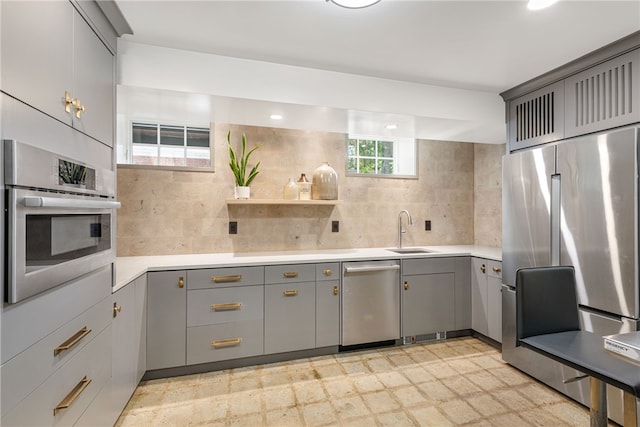 349 Wayland Ave, Providence, RI 02906 - kitchen with gray cabinetry, stainless steel appliances, a sink, backsplash, and light countertops