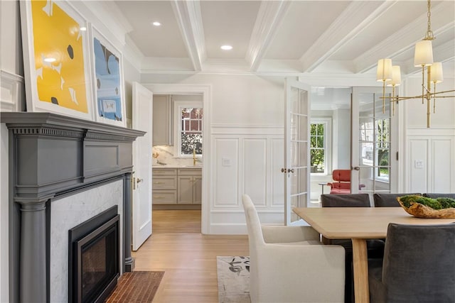 349 Wayland Ave, Providence, RI 02906 - dining area featuring a decorative wall, a fireplace with flush hearth, ornamental molding, light wood-style flooring, and beam ceiling