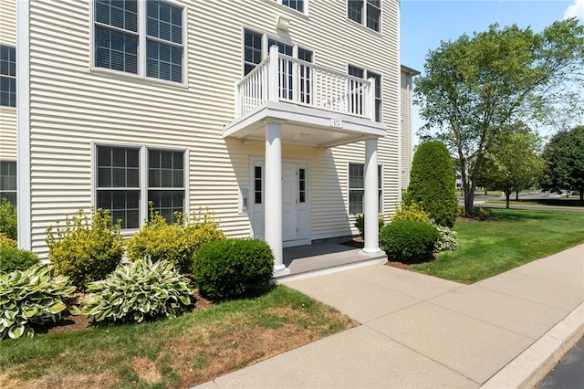 doorway to property with a lawn and a balcony