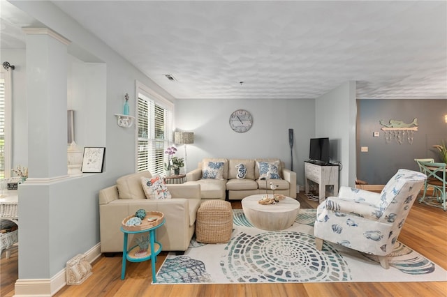 living room with baseboards, visible vents, and wood finished floors