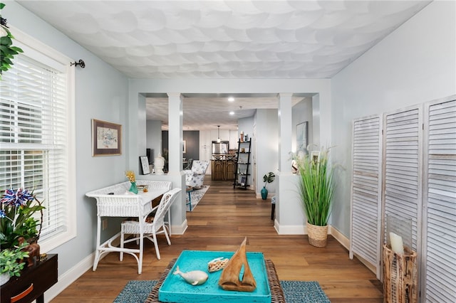 interior space with ornate columns, baseboards, and wood finished floors
