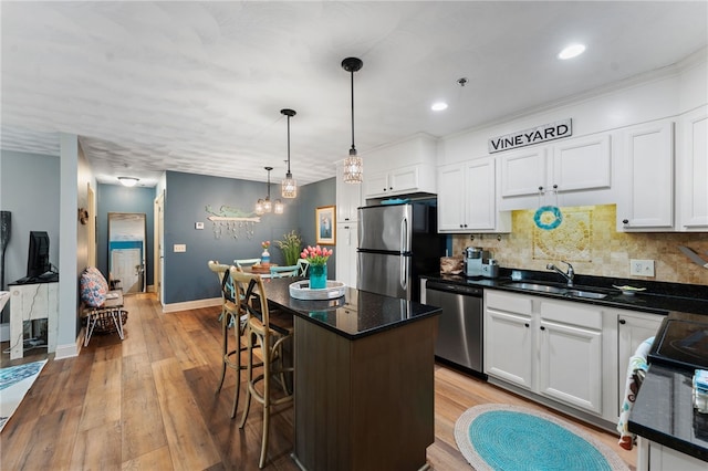 kitchen with white cabinetry, tasteful backsplash, a sink, light wood-style flooring, and appliances with stainless steel finishes
