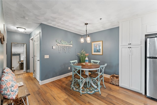 dining space featuring baseboards and light wood-style flooring