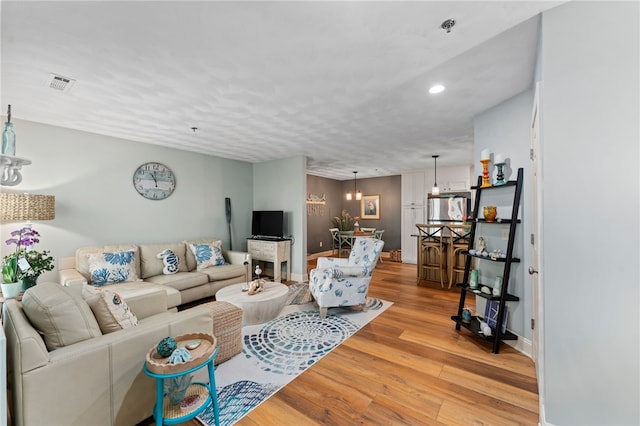 living room featuring visible vents, baseboards, a chandelier, recessed lighting, and light wood-style flooring