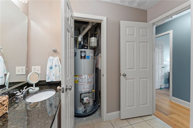 bathroom with water heater, baseboards, tile patterned flooring, and vanity