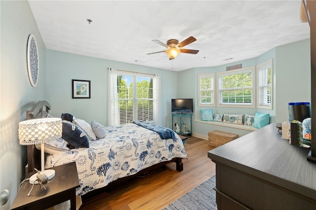 bedroom featuring baseboards, ceiling fan, wood finished floors, and visible vents