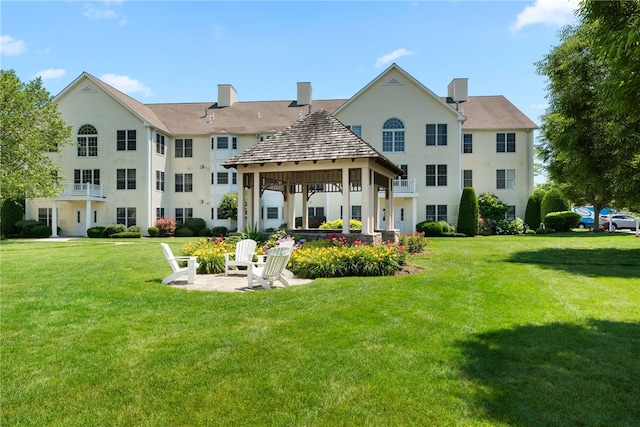 rear view of property featuring a lawn, a gazebo, and a chimney