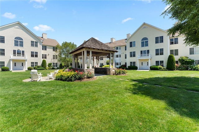 rear view of property featuring a lawn and a gazebo