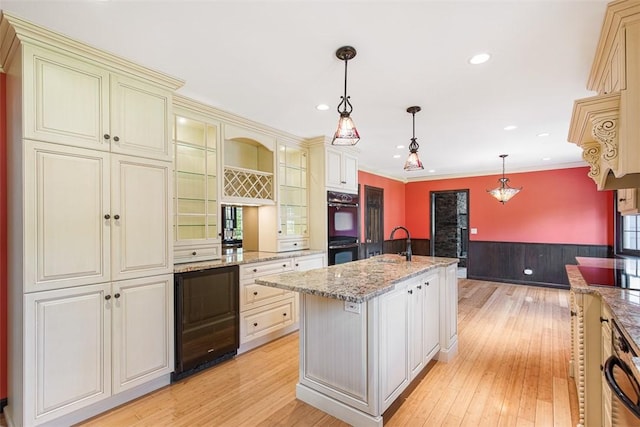 28 Potter Hill Rd, Westerly, RI 02891 - kitchen with cream cabinetry, wainscoting, light wood-style flooring, a sink, and hanging light fixtures