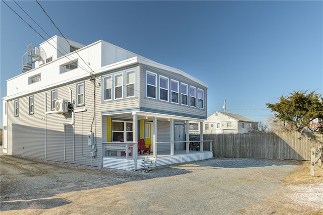 rear view of property featuring a porch, ac unit, and fence