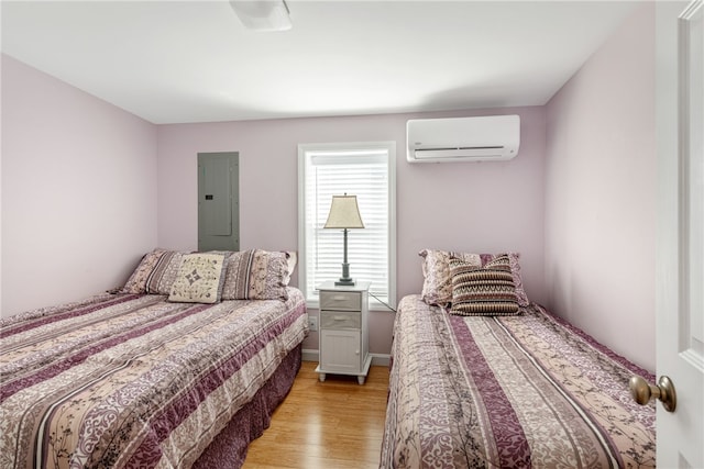 bedroom with light wood-style flooring, a wall mounted AC, and electric panel