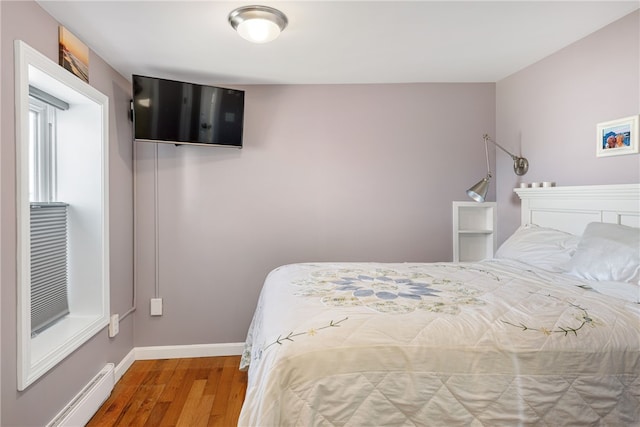 bedroom featuring baseboards, baseboard heating, and wood finished floors