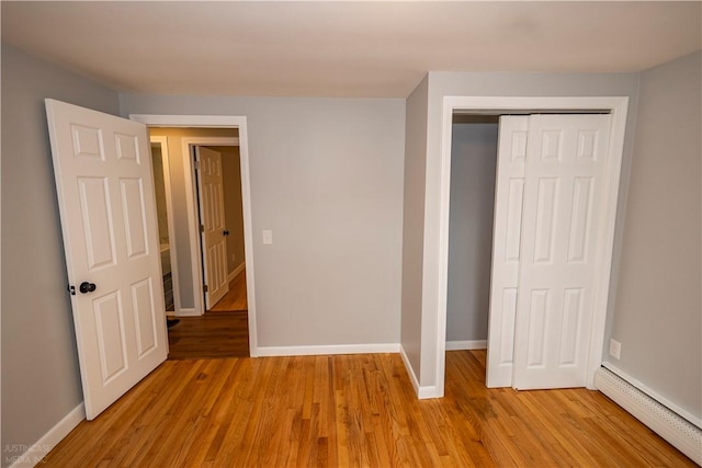 2 King St, Johnston, RI 02919 - unfurnished bedroom featuring a closet, light wood-style floors, baseboards, and a baseboard heating unit