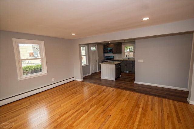 2 King St, Johnston, RI 02919 - unfurnished living room featuring a baseboard radiator, baseboards, plenty of natural light, and wood finished floors