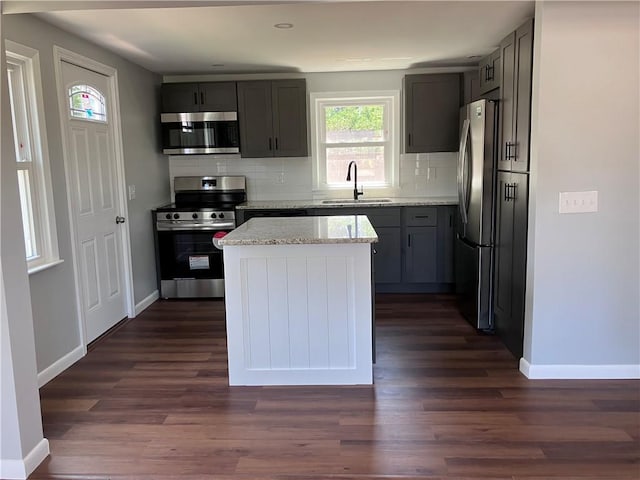 2 King St, Johnston, RI 02919 - kitchen featuring appliances with stainless steel finishes, a center island, tasteful backsplash, dark wood-style flooring, and light stone counters