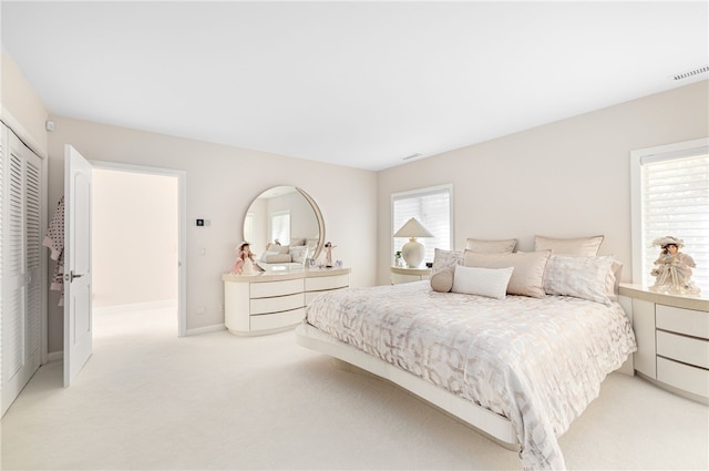 bedroom featuring baseboards, light carpet, a closet, and visible vents