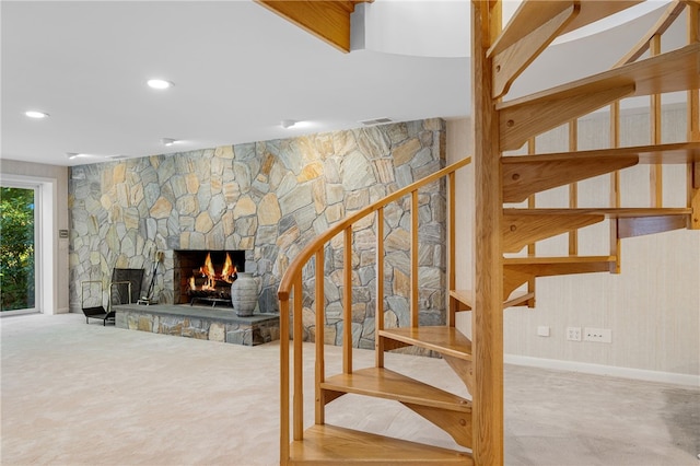 stairs with baseboards, a stone fireplace, visible vents, and recessed lighting