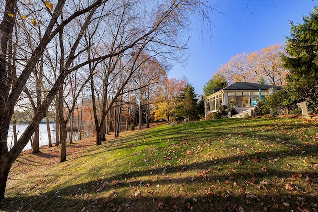 view of yard featuring a sunroom and a water view