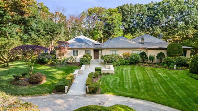 ranch-style home featuring stucco siding and a front lawn