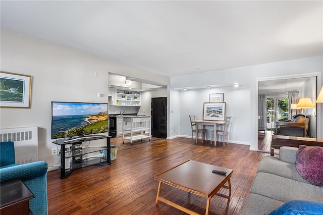 living area with wood finished floors and radiator heating unit