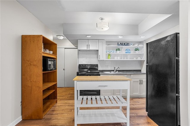 kitchen featuring black appliances, light wood-style flooring, open shelves, and decorative backsplash