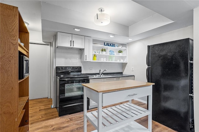 kitchen featuring a sink, open shelves, black appliances, and tasteful backsplash