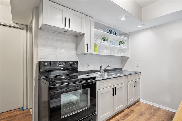 kitchen featuring a sink, electric range, white cabinets, light wood-type flooring, and tasteful backsplash