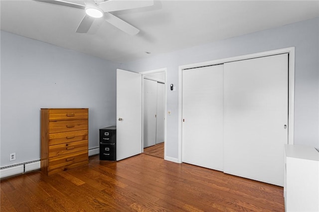 unfurnished bedroom with a closet, wood finished floors, ceiling fan, a baseboard radiator, and baseboard heating