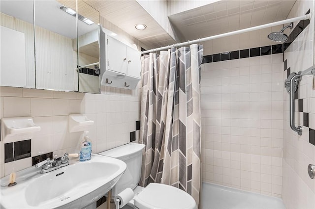 bathroom with a sink, toilet, a stall shower, and tile walls