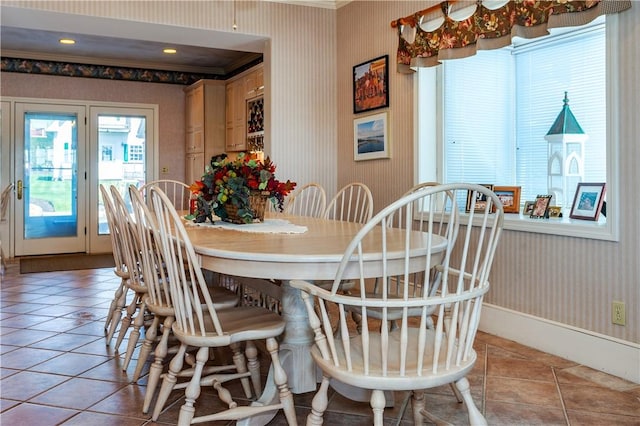 dining room with wallpapered walls, ornamental molding, light tile patterned floors, and baseboards