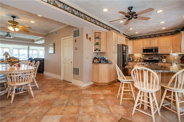 kitchen with stainless steel appliances, a ceiling fan, crown molding, recessed lighting, and a breakfast bar area