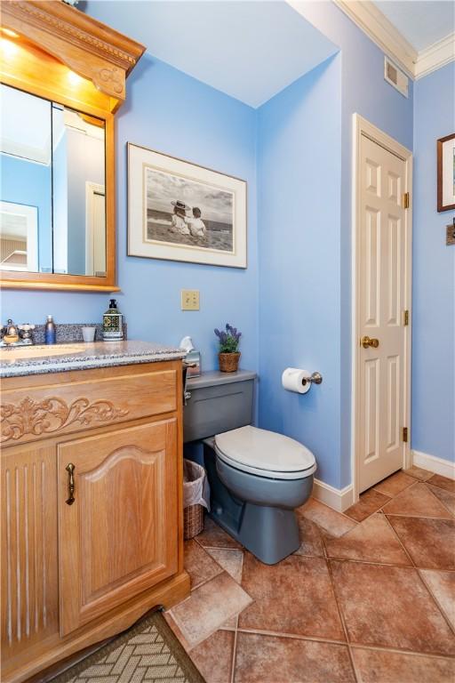 bathroom featuring toilet, vanity, baseboards, and ornamental molding