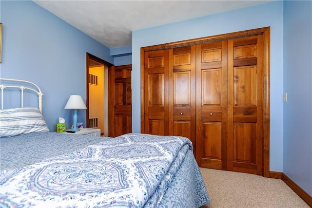 carpeted bedroom featuring a closet and baseboards