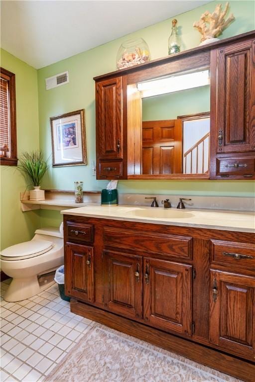 half bath featuring toilet, vanity, and tile patterned flooring
