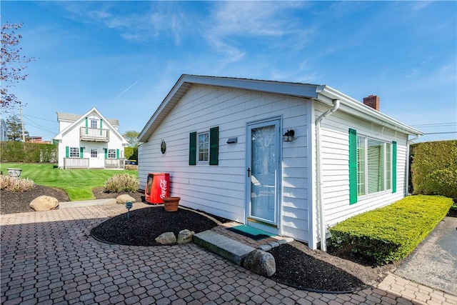 back of house featuring a chimney, a patio, and a yard