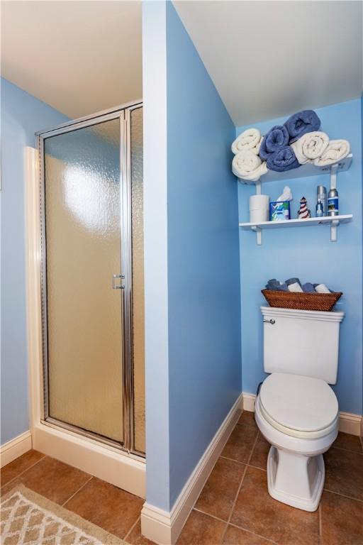 full bathroom featuring tile patterned floors, a shower stall, baseboards, and toilet
