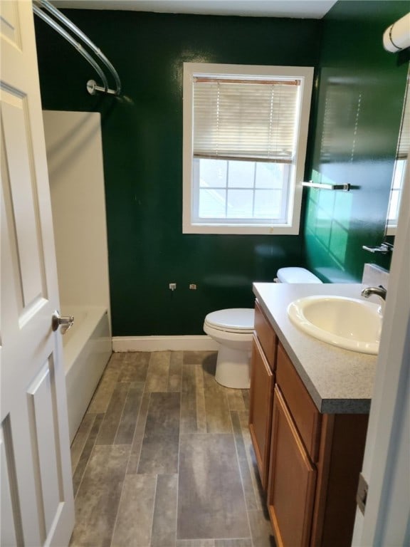 bathroom with vanity, toilet, washtub / shower combination, and wood finished floors