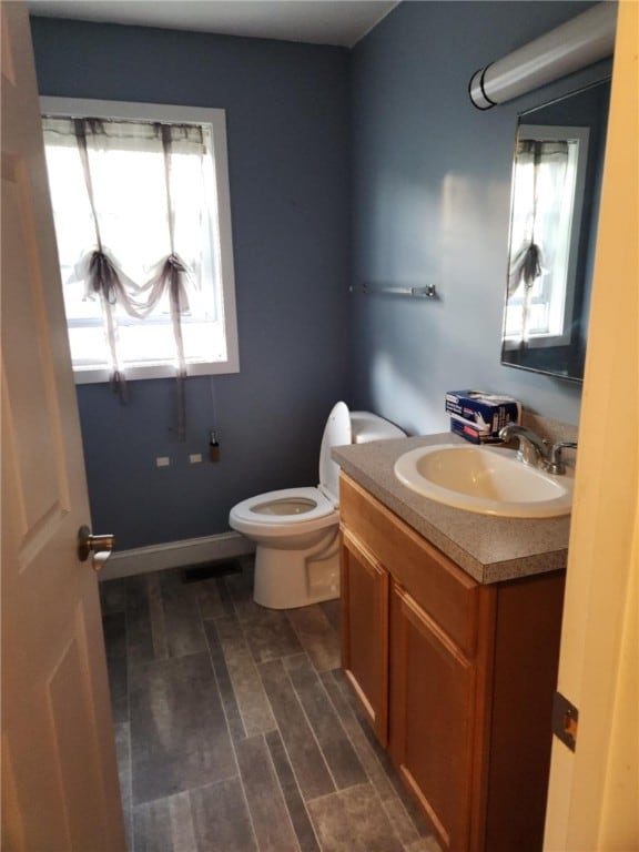half bathroom with vanity, plenty of natural light, and toilet
