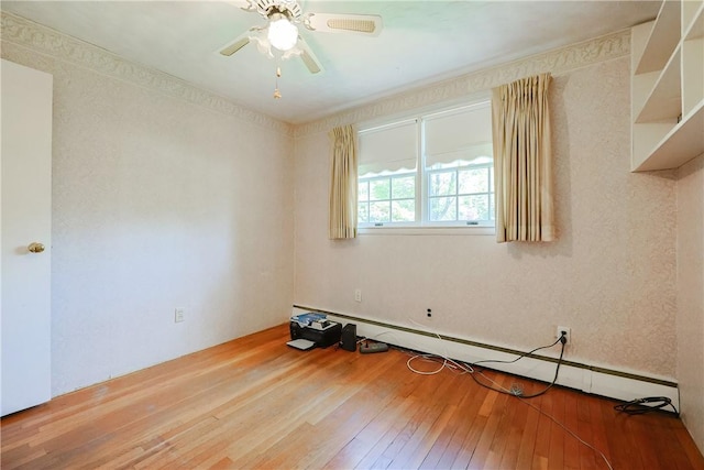 empty room featuring ceiling fan, hardwood / wood-style flooring, and a baseboard heating unit